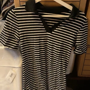 Svartvit randig pikéklänning  - Säljer en svartvit lång randig pikéklänning med svart krage och v-ringning. 