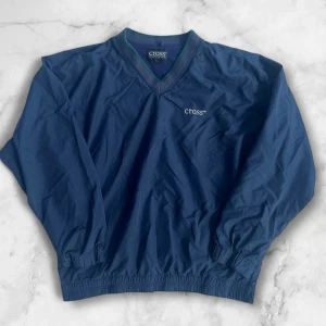 Blå v-ringad tröja från Cross Sportswear - Säljer en blå v-ringad tröja från Cross Sportswear i storlek XXL. Tröjan har långa ärmar, elastiska muddar och en diskret logga broderad på bröstet. Perfekt för en sportig och avslappnad stil.