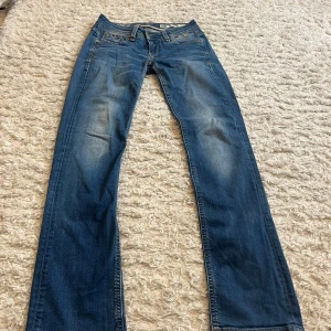 Blå jeansbyxor från Tommy Hilfiger Denim - Säljer ett par snygga Low waist blå jeansbyxor från Tommy Hilfiger Denim med raka byxor. Innerbenslängd:77 midjemått: 36 cm tvärs över. Storlek: 26W 32L