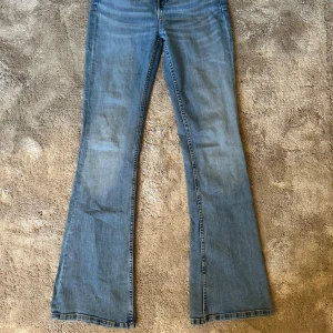 Blå flared high waist jeans från Zara - Säljer ett par klassiska flared high waist blå jeans från Zara. Jeansen har normal passform, fickor och stängs med dragkedja och knapp. Använda endast en gång, har inga defekter och ser ut som nya.