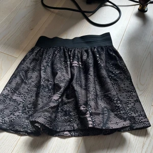 Svart spetskjol från Cubus( är för barn) - Säljer en svart kjol från Cubus i storlek 134. Kjolen har ett brett resårband i midjan och är täckt av ett vackert spetslager med blommigt mönster. 