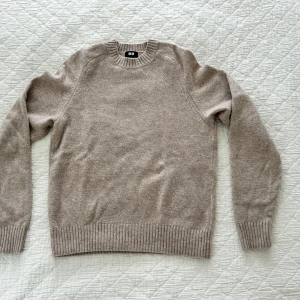 Beige ulltröja från Uniqlo - Säljer en klassisk beige stickad tröja från Uniqlo i 100% ull. Tröjan har rund halsringning, långa ärmar och ribbade muddar vid ärmslut och nederkant. 