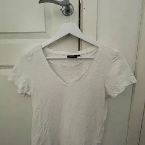 Vit v-ringad t-shirt från Kappahl  - En klassisk vit t-shirt från Kappahl med v-ringning och korta ärmar. Perfekt basplagg i mjuk bomull som passar till det mesta. Enkel och stilren design. Skriv för frågor eller diskutera pris!!