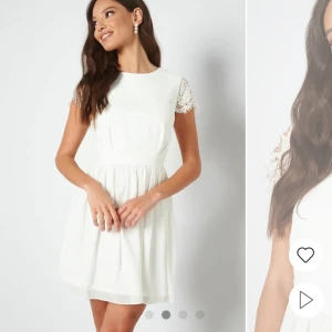 Vit klänning med spetsdetaljer - Säljer en söt vit klänning med spetsdetaljer på ärmarna. Klänningen har en rund hals och en kort kjol som ger en luftig känsla. Perfekt för sommarens alla tillfällen! Använd 1 gång. Små defekter kan förekomma. 