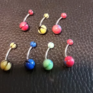 Färgglada navelpiercingar i olika färger - Säljer 7 st navelpiercingar med kulor i olika färger som gul, blå, grön och röd. (Kirurgiskt stål) Kulorna har ett mönster med svarta detaljer. Perfekt för dig som vill variera din stil med färgglada accessoarer. Aldrig använda.