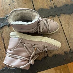 Beige/rosa  boots från Inuikii med snörning - Säljer ett par beige boots från Inuikii med snörning och mjukt foder. Skorna har en rund tå och platt sula, perfekta för kyligare dagar. Utsidan är i skinn och insidan är fodrad med päls för extra värme. Nypris ca 2500kr. Sparsamt använda 