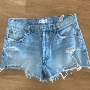 Ljusblå jeansshorts med slitningar från Zara - Ljusblå jeansshorts från Zara  och flera slitningar framtill och baktill. A