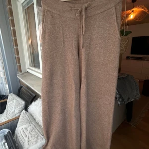 Beige stickade byxor från KAY/day - Mysiga beige stickade byxor från KAY/day med bred resår och knytband i midjan. Byxorna har en rak och loose passform. Väldigt stor i storleken mer som en M/L