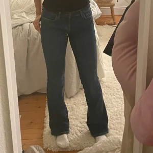 Blå bootcut jeans - Säljer ett par klassiska blå bootcut jeans med normal passform. Jeansen har fem fickor, dragkedja och knapp framtill. Perfekta till vardags och lätta att matcha med olika toppar.