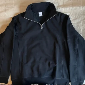 Svart halvzip-tröja från Zara - Säljer en svart långärmad halvzip-tröja från Zara. Tröjan har hög krage med dragkedja och är tillverkad i ett mjukt material. Skicket är helt nytt aldrig använd. Det är bara att höra av sig vid minska lilla fundering!