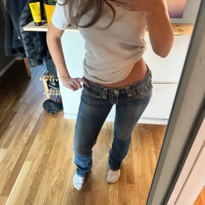 Mörkblå jeans från True Religion - Snygga mörkblå jeans från True Religion med låg midja och bootcut-stil. Jeansen har dekorativa sömmar och en klassisk femficksdesign. Perfekta för en avslappnad look. Kostar 1000-1400kr i butik men har sänkt till 500 kr. Lånade bilder