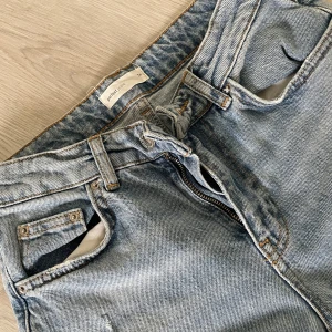 Ljusblå slitna jeans med hål - Ljusblå jeans från Pull&Bear med slitningar och stora hål på benen. Klassisk femficksmodell med dragkedja och knapp. Jeansen har en rak passform och är tillverkade i denim.💗🤘