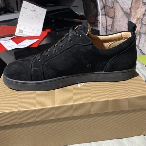   Christian Louboutins  - Säljer ett par svarta sneakers f Christian Louboutin från CNFans med ovandel i mocka och klassisk röd sula. Skorna har svarta skosnören och en stilren design med rund tå. Innersulan är beige med guldlogga. Kommer med originalkartong och kvitto använda fast i väldigt bra skick pris kan diskuteras.