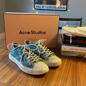  sneakers från Acne Studios - Säljer ett par gröna sneakers från Acne Studios med vitt mönster och vita snören. Skorna har rund tå, platt sula och klassisk sneakerdesign. Kommer med originalpåse och box. Perfekta för dig som gillar stilrena men unika skor. Strl 40! 