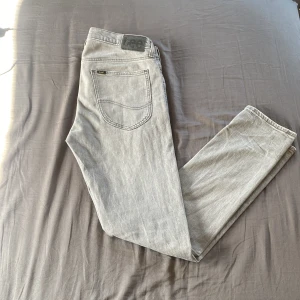 Ljusgrå jeans från Lee - Säljer ett par ljusgrå jeans från Lee med klassisk femficksdesign och Lee-logga på bakfickan. Jeansen har normal/slim passform och raka ben. Perfekta för dig som gillar en stilren och enkel look. Pris kan sänkas vid snabb affär. Vid fler frågor är de bara att höra av dig. Mvh Oliver 