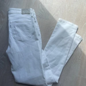 Vita Levi's 712 Slim jeans - Snygga vita Levi's 712 Slim jeans med klassisk femficksdesign och raka ben. Jeansen har en slim passform och är tillverkade i mjuk bomull med lite stretch för extra komfort. Perfekta för dig som vill ha en clean och fräsch look.