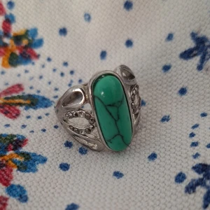 Ring med grön sten - Cool silverring med en avlång grön sten i mitten och snygga utskurna detaljer på sidorna. Stenen har svarta ådror som ger en unik look och ringen har en vintagevibe. En sten fattas på ena sidan, två stenar fattas på andra. 