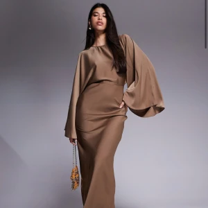 Brun långklänning med vida ärmar - Från Asos! Supersnygg brun långklänning i satinliknande material med dramatiskt vida, långa ärmar och figurnära passform. Perfekt för dig som vill sticka ut med en elegant och modern look. Jag säljer den eftersom den är för liten. Den är använd knappt en gång och har etiketten kvar! Nypris: 929kr