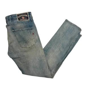 Replay ljusblå slitna jeans - Säljer ett par ljusblå jeans från Replay med snyggt slitna detaljer och patch på bakfickan. Jeansen har klassisk femficksdesign, raka ben och är tillverkade i mjukt denimtyg. Perfekta för en avslappnad streetstil. 30/32