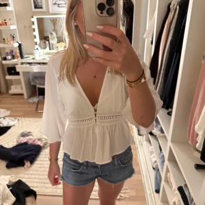 Vit blus med knappar från Zara - Supersöt vit blus från Zara med v-ringning, trekvartsärmar och dekorativa knappar framtill. Använd några gånger, inga defekter💕