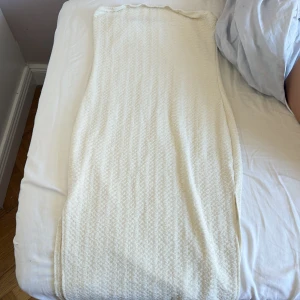 Vit klänning i stickat material - En stilren vit klänning i stickat material med diskret struktur. Klänningen har rak passform och är perfekt för dig som gillar en enkel men trendig look. Passar snyggt med både sneakers och boots.