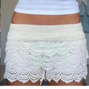 Vita virkade spets-shorts med volang - Superfina vita shorts med bred resår i midjan och flera lager volang i virkad spets. De har en feminin och bohemisk vibe, perfekta för varma dagar. Snyggt mönstrade kanter och mjukt material som känns luftigt och bekvämt. De är kräm vita, skriv för funderingar💗