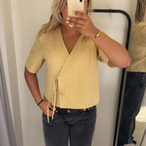 Gul och vit rutig omlottblus Lindex - Superfin gul och vit rutig omlottblus från Lindex med korta ärmar och knyt i sidan. Aldrig använd tyvärr, passar även S!