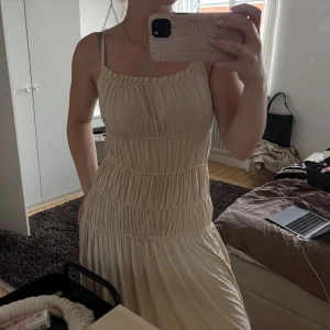Beige långklänning från NA-KD XS - Supersöt långklänning från NA-KD i beige med smala axelband och rynkade detaljer över hela klänningen.