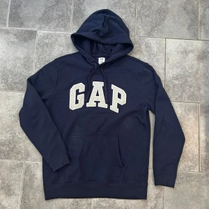GAP hoodie  - En GAP marinblå hoodie som inte är använd. Hoodie passar perfekt både till S och M. Tröjans märke är i grå med vita kanter och snören som är justerbara. Hör av dig vid fundering. MVH LUNDGRENS