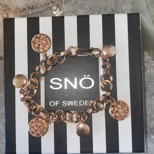 Guldigt armband från SNÖ of Sweden - Charmigt armband i guldton från SNÖ of Sweden med stora länkar och flera runda berlocker, varav några är glittriga och andra blanka. Perfekt statement-piece med snygg kedjedesign och detaljer som fångar ljuset. Asså fick den för min födelsedag som var 1 juni och den är på riktigt knappt använd då jag gillar silver!! Men den är lite mer av en champagne guld. Hittar den inte på hemsidan så är säkert slutsåld men kostade runt 500+ om ja kmr ihåg rätt. Om de är ngt så tveka it att fråga ❤️❤️