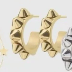 Guldiga Edblad örhängen med nitar  - Coola örhängen i guld med chunky design och spetsiga nitar runt hela ringen. Perfekta för dig som vill sticka ut och ge din look en edgy vibe. Passar både till streetstyle och när du vill addera lite attityd till outfiten.