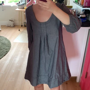 Grå klänning med trekvartsärm - Enkel och stilren grå kortklänning i bomull med trekvartsärmar och rundad, djup urringning. Klänningen har veck framtill och avslappnad passform, perfekt för en chill och bekväm look. Den har dessutom fickor, storleken är XS, men den är för stor för mig som bär S. 