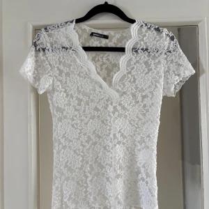 Vit spetstopp - Superfin vit topp i spets från Gina Tricot med blommigt mönster och v-ringad kant med vågig detalj. Kortärmad och figurnära passform. Skulle dock säga att den är lite liten i storleken. 
