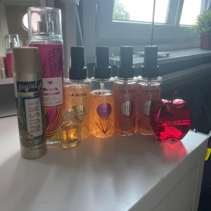Parfym/body mists  - Säljer ett paket med flera parfymer och body mists: fyra La Rive body mists (Golden Dream, Sparkling Rose, Brown Orchid), Beach Coconut body mist (236 ml), Impulse Hint of Musk body fragrance (75 ml), en liten parfymflaska i märket revolution och en röd äppelformad flaska (20ml).                                         Skriv gärna vid intresse!🫶🏼