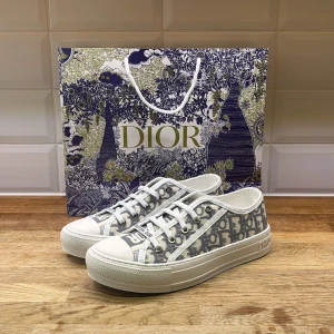 Dior skor  - Snygga Dior sneakers med klassiskt grått och vitt monogrammönster, vita snören och robust vit platt sula med svart stjärndetalj undertill. Ovandel i textil och detaljer i skinn. Perfekta för dig som vill sticka ut med lyxig streetstyle. Inne sulorna e lite skadade och fläck som syns på insidan men inget märks vi användning  