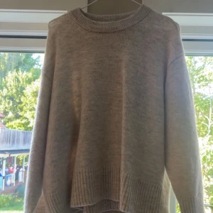 Beige stickad tröja från Gina Tricot - Mysig beige stickad tröja från Gina Tricot i storlek 158/164. Tröjan har rund halsringning, ribbade muddar och en loose passform. Perfekt för lager-på-lager och chill dagar. Enkel och stilren design som funkar till det mesta.