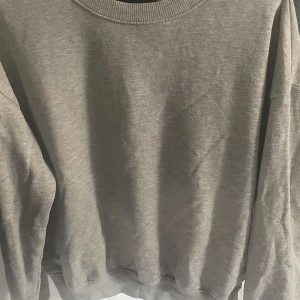 Grå sweatshirt från 157 i bomull - Enkel och stilren grå sweatshirt från 157 i storlek S. Tröjan har rund halsringning, ribbade muddar vid ärmslut och nederkant samt är tillverkad i mjuk bomullsmix. Perfekt för en chill och avslappnad look.