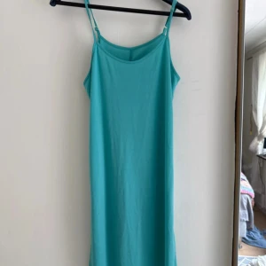 Turkos ärmlös sommarklänning - Enkel och snygg turkos klänning med smala axelband och rak passform. Klänningen är ärmlös och har en mjuk, bekväm känsla, perfekt för varma dagar. 