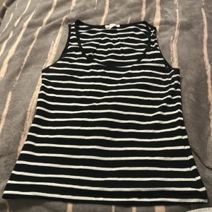 Randig linnetopp från Amisu - Säljer en svartvit randig linnetopp från Amisu i storlek L. Toppen är ärmlös med klassisk rund halsringning och raka linjer. Tillverkad i mjuk bomull, perfekt för en chill och stilren look. Passar dig som gillar enkel och tidlös stil.