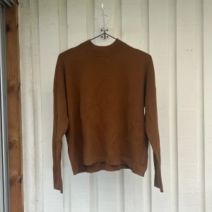Brun stickad tröja med hög hals - En enkel och snygg brun stickad tröja med hög hals och långa ärmar. Perfekt för lager-på-lager och passar till både jeans och kjol. Tröjan har en loose passform och är supermjuk mot huden.