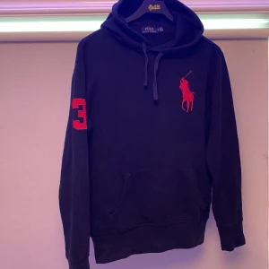 Svart hoodie Polo Ralph Lauren röd logga - Svart hoodie från Polo Ralph Lauren big pony hoodie väldigt ovanlig tröja därav priset inga skador eller nått bara höra av dig till os så är vi här för att besvara dina frågor.