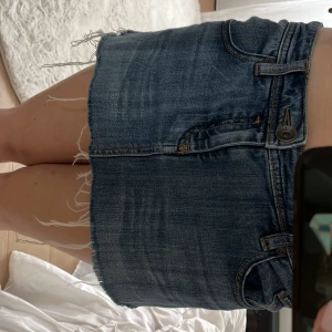 Jeanskjol från Esprit med fransig kant - Säljer en snygg blå mini jeanskjol från Esprit med rå, fransig kant nertill. Klassisk femficksmodell med knapp och dragkedja framtill. Perfekt för dig som gillar en avslappnad och trendig stil.