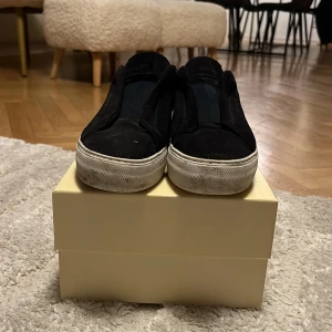 Tja säljer ett par Svarta Axel Arigato, Storlek 41-42. Pris 1500 men de går att diskutera. Det är bara att ställa frågor har ej kvitto men en nk påse om ni vill ha bild på det. - Svarta slip-on sneakers från Axel Arigato med ovandel i mocka och vit platt sula. Diskret logga i guld på sidan och minimalistisk design. Perfekta för dig som gillar stilrena och cleana skor med en lyxig känsla.