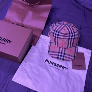 Burberry rutig keps beige  - Snygg keps från Burberry i klassiskt beige rutigt mönster med Justerbar baksida med svart spänne och Burberry-logga. Perfekt accessoar för en trendig look.