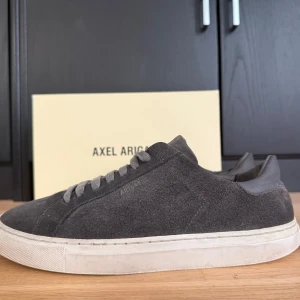 Grå mockasneakers från Axel Arigato - Tja säljer ett par snygga  grå sneakers från Axel Arigato i mocka. Det är egentligen för killar men tjejer kan också ha på sig de. Passar till storlek 40 men även 41. De har blivit lite små för mig och därför säljer jag dem, hör av er vid intresse👍