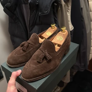 Crockett & Jones skor - Tasselloafers med ovansida i läder från den engelska skotillverkaren Crockett & Jones. Tillverkade för hand med yttersta omsorg i deras fabrik i Northampton. skorna är väl omhändertagna det som skulle behövas är kanske att byta ut sulan annars tycker jag de ser jättefina ut. Ny pris 7,999kr (kvitto följer med) 