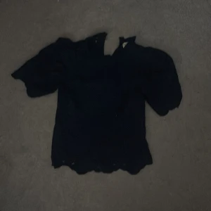 Svart blus Holly & Whyte XS - Supersöt svart blus från Holly & Whyte by Lindex i storlek XS. Blusen har korta puffärmar och en vågig kant nertill. Perfekt för dig som gillar en feminin och stilren look. Lätt och luftig, passar till många outfits. Trasig i knäppet, lätt o laga, märks knappt derföe nedsatt pris 