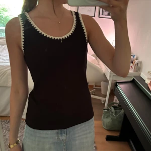 Svart ribbat linne - Snyggt svart ribbat linne med vit taggig kant. Helt oanvänd med prislapp kvar, säljer då det tyvärr är för stort för mig <3