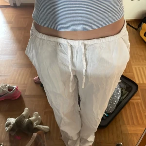 Vita linnebyxor med snörning - Säljer ett par vita linnebyxor med avslappnad passform och snörning i midjan. Perfekta för varma dagar och riktigt sköna att ha på sig. Byxorna har elastisk midja och raka ben för en chill vibe.