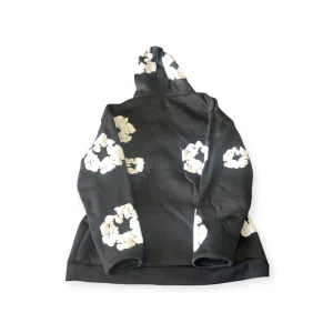 denim tears Svart hoodie med vita blommor - Svart hoodie med stora vita blommönster över hela tröjan. Tröjan har huva och långa ärmar, perfekt för dig som gillar en chill och trendig stil. Mjuk och skön, passar till många olika outfits.